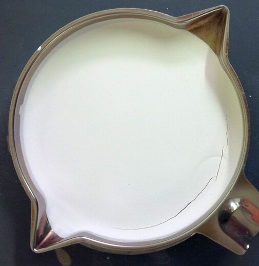 A tray, dried under a heat lamp, with a layer of powder glaze on the bottom