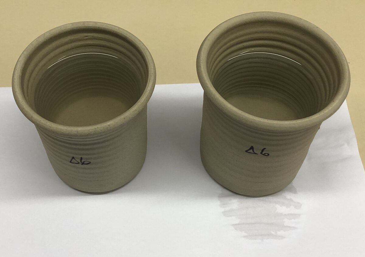 An unglazed stoneware mug leaks water