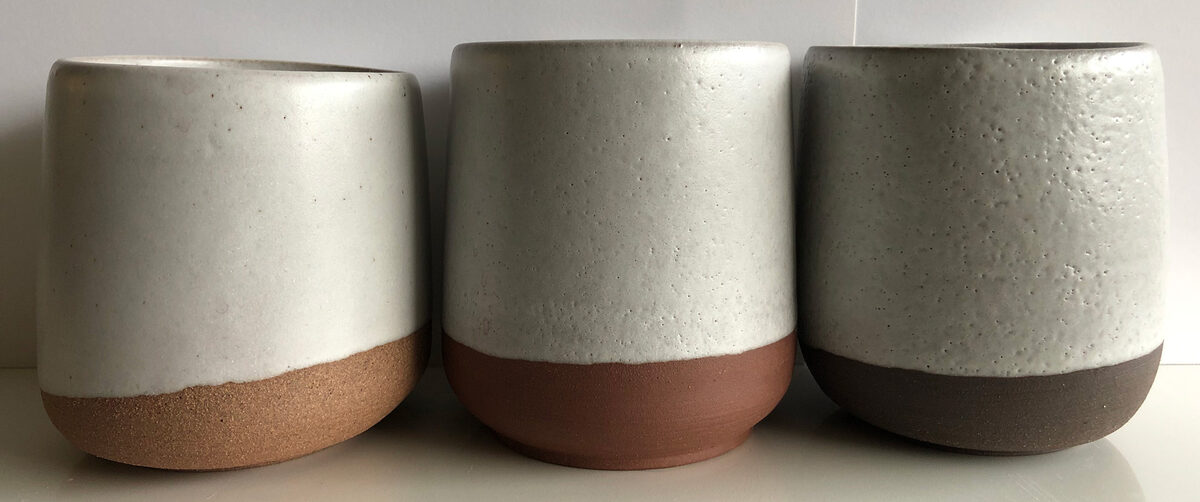 Three pottery mugs, two having glaze pinholes