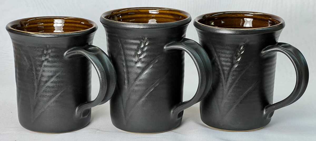 Three matte black pottery mugs