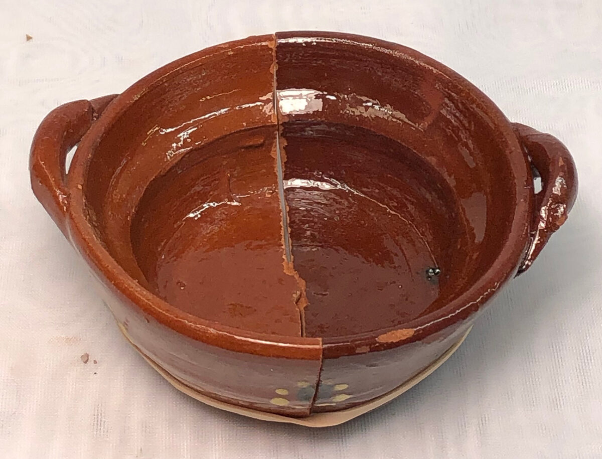 Two halves of a terra cotta bowl, one refired