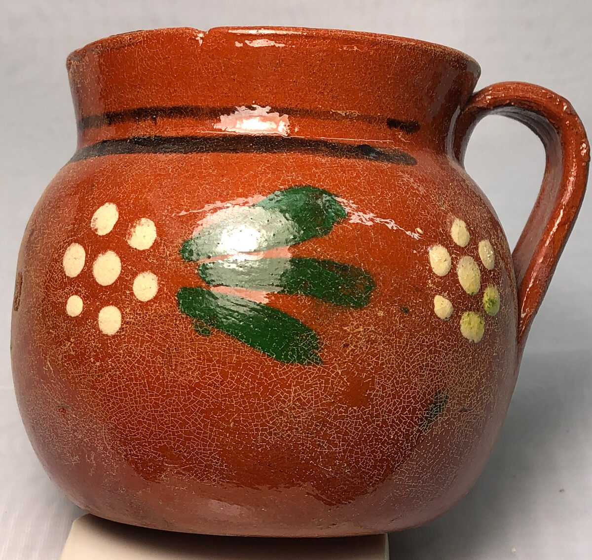 A terra cotta clear-glazed vessel with dissolved lead powder left behind on the surface